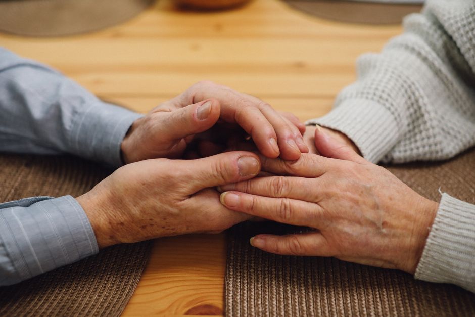 ehepaar haende halten holztisch naehe begleitung palliativpflege