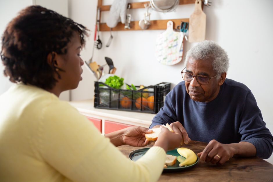 ernährung pflegebedürftige pflegerin hilft senior essen mahlzeit zuhause