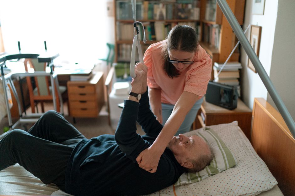 pflegeperson hilft senior mann schlaganfall nachsorge zuhause ambulante betreuung