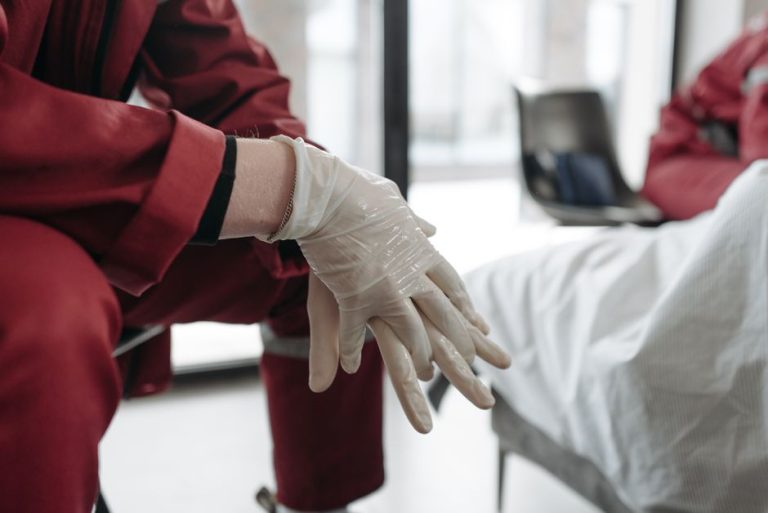 schutzkleidung pflege pflegekraft rote uniform handschuhe anziehen hygiene